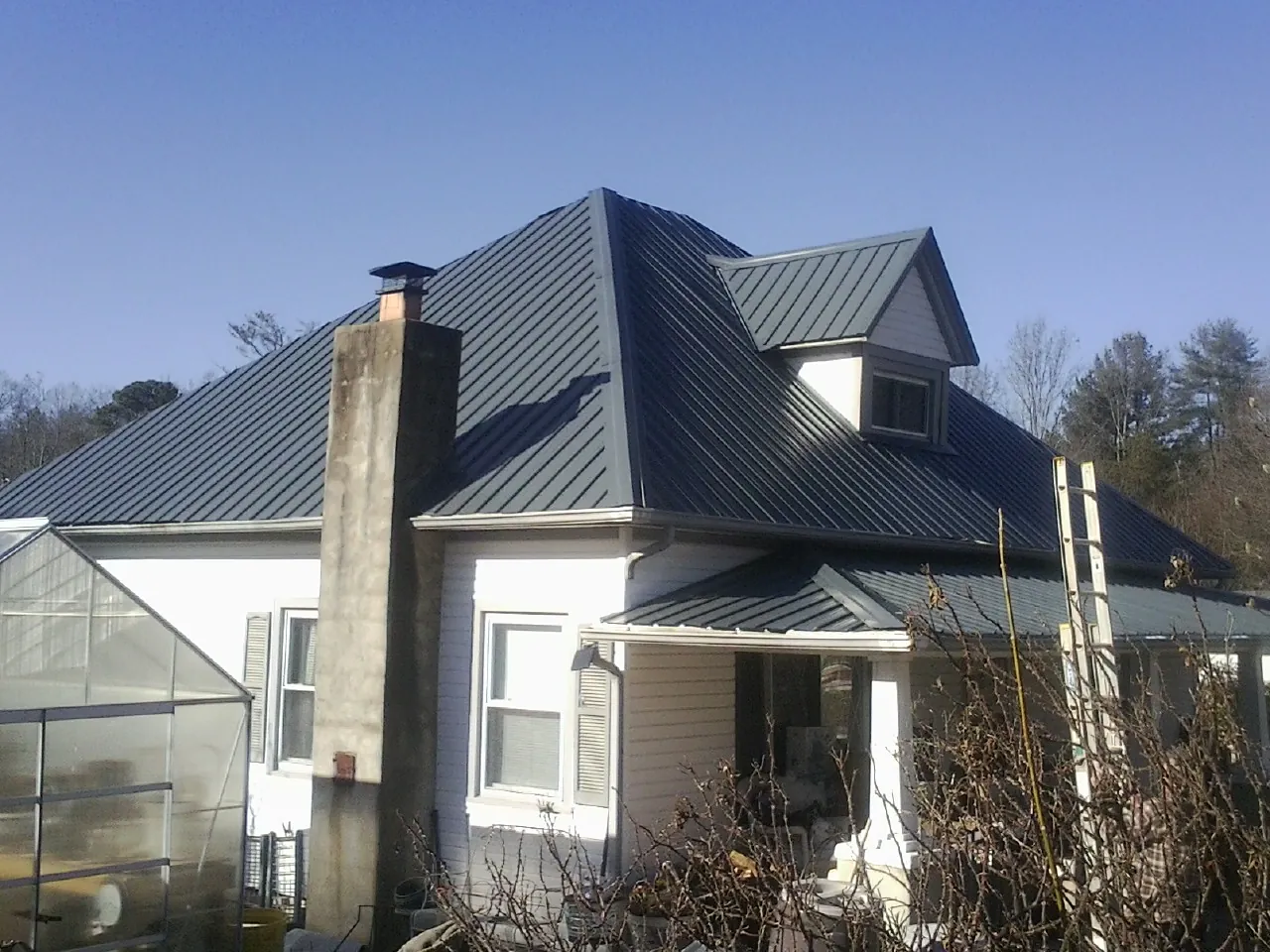 Dark blue standing seam metal roof on a white farmhouse with dormer — Slate & Tile Roof Repair by Roofing Brothers in Waxahachie