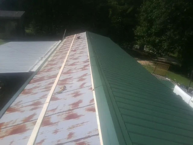 Old rusted panels beside newly installed green metal roofing — Wind Damage Roof Repair by Roofing Brothers in Waxahachie