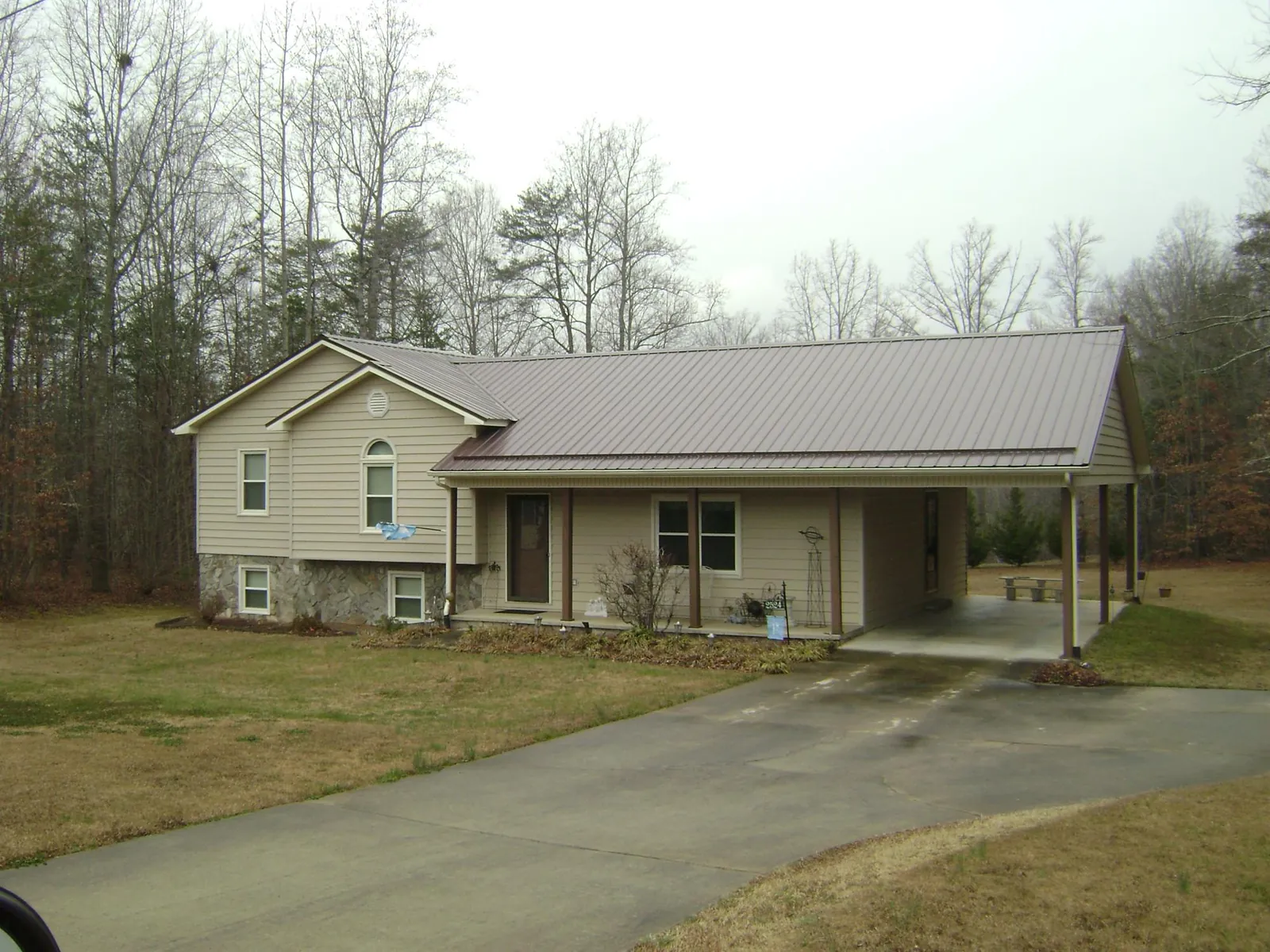 Brown metal roof on a tan split level home with an attached carport in Waxahachie