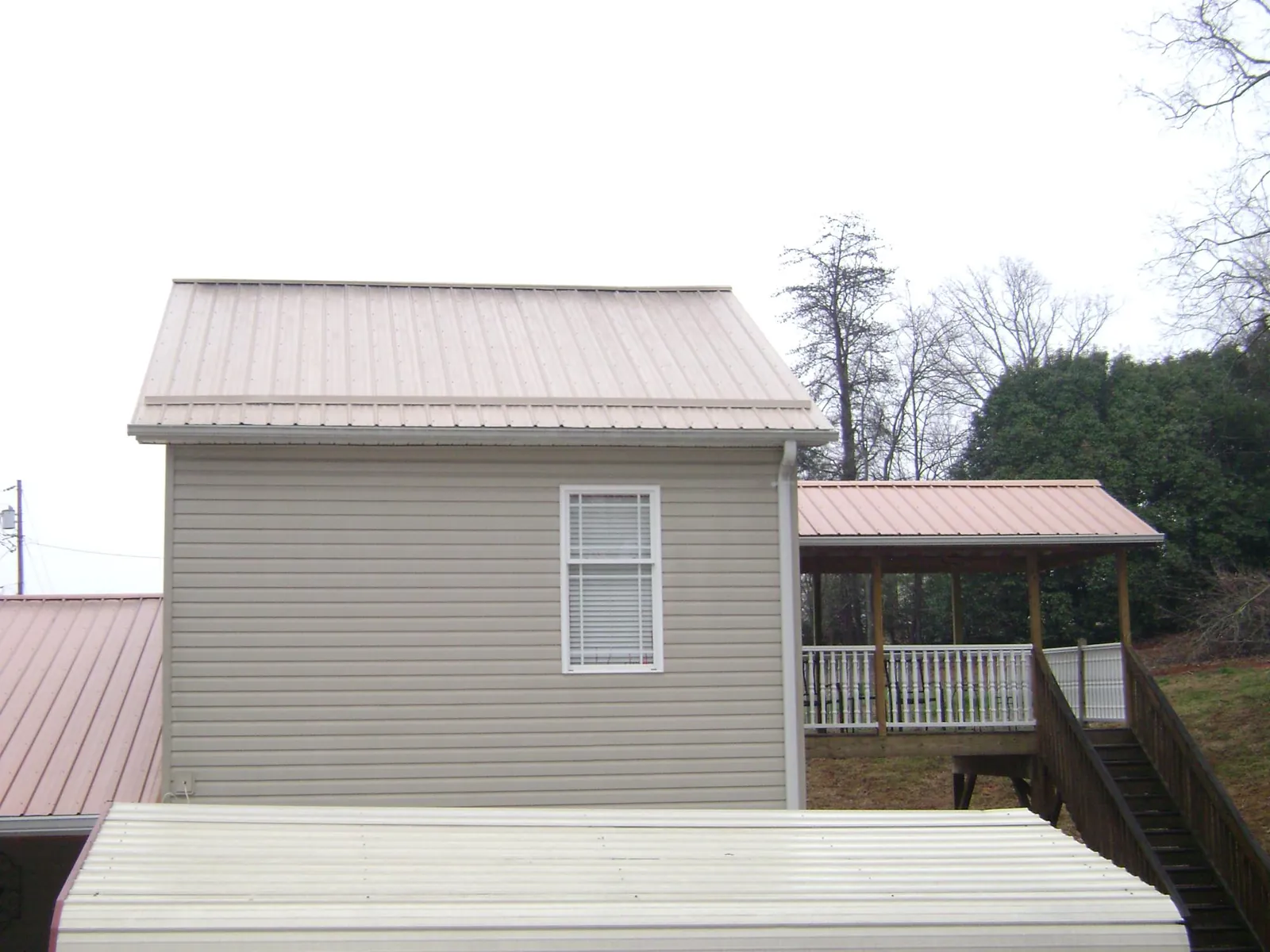 Tan metal roofs on a two story addition and attached porch, from a Roof Replacement job in Waxahachie