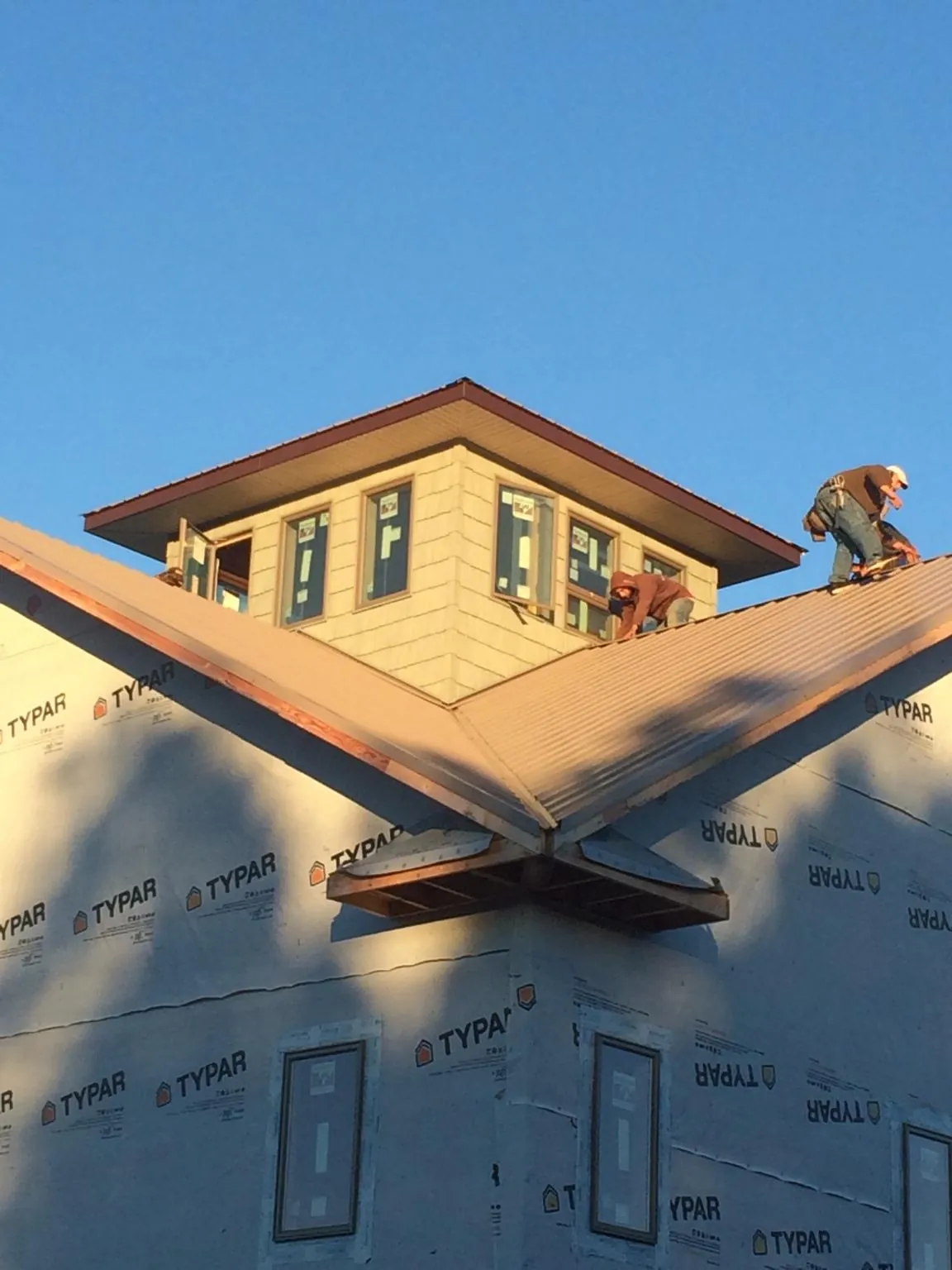 Roofers working around a rooftop cupola on a new metal roof at sunset — Roof Waterproofing in Waxahachie by Roofing Brothers
